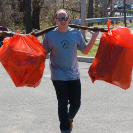 Volunteers carry away litter from the stream banks.